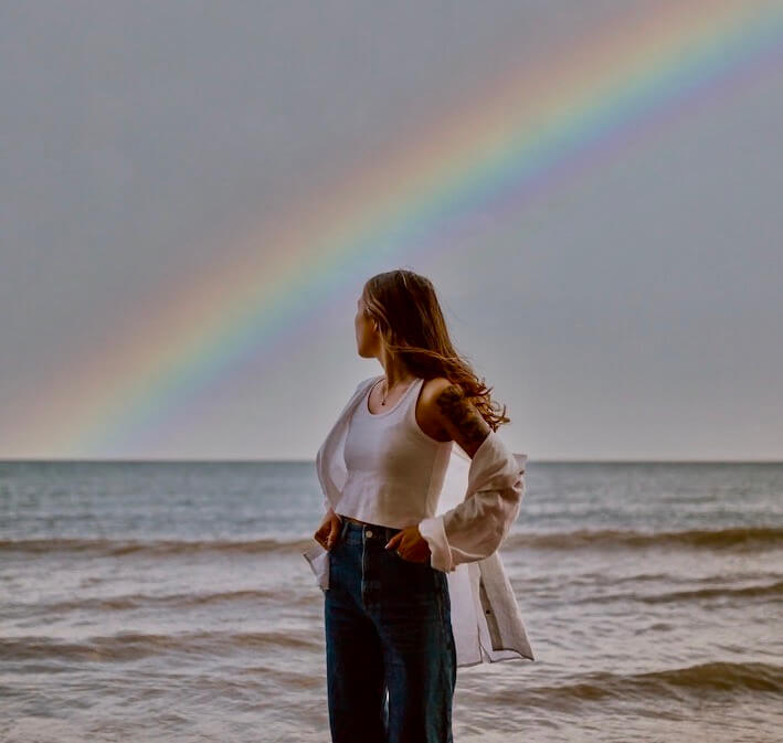 woman standing with a rainbow behind her
