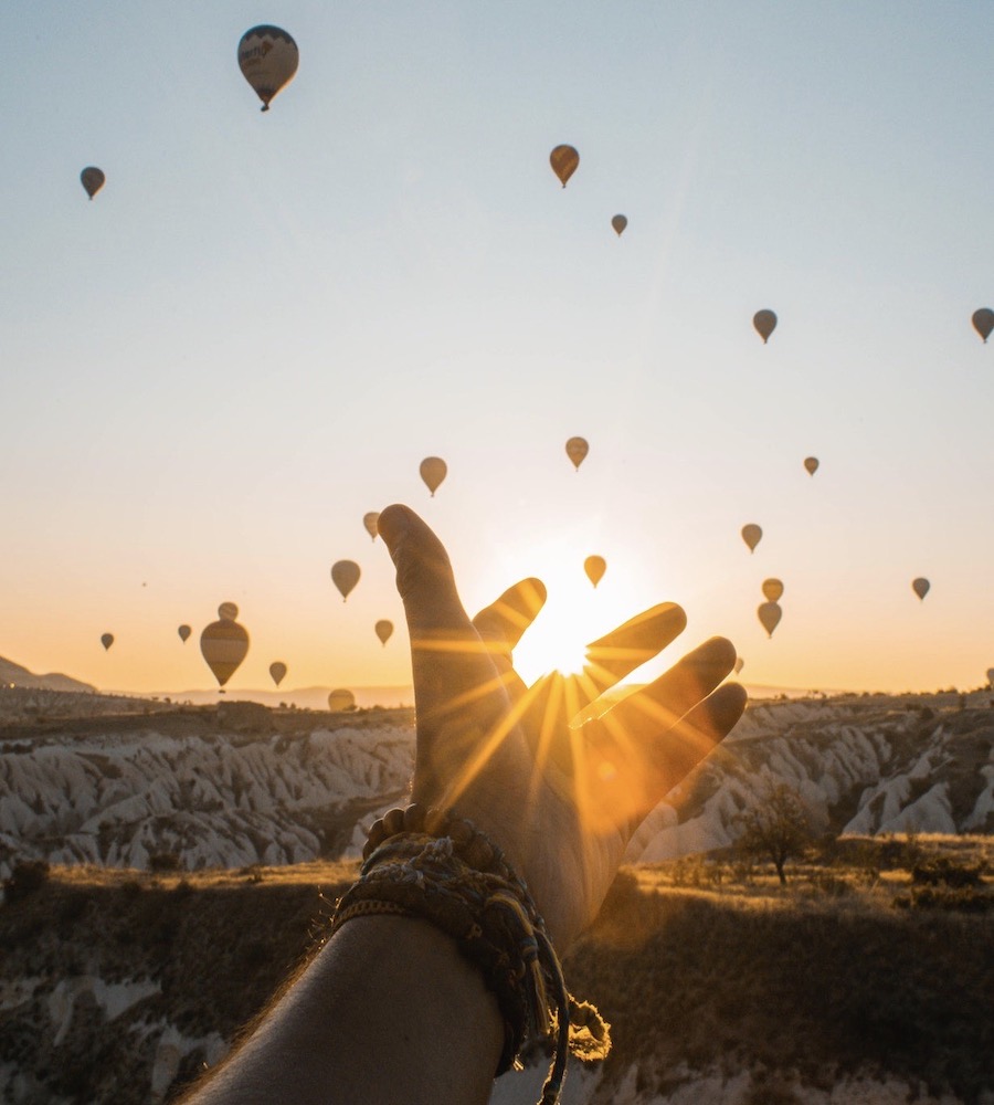 hand reaching in sunset for hot air balloons