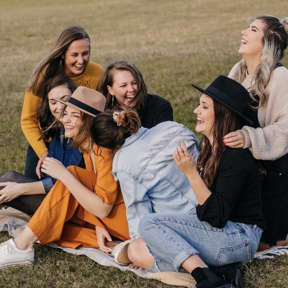 women sitting on grass laughing