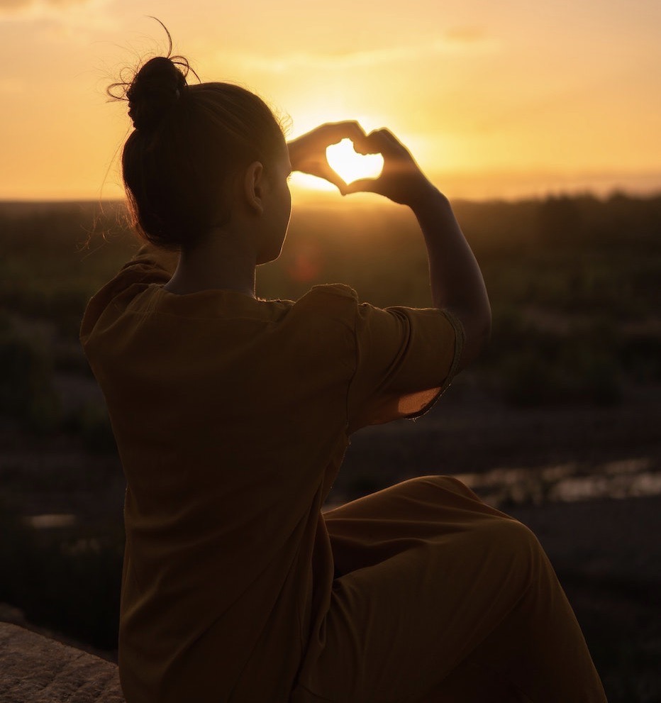 woman making heart shape in the sun