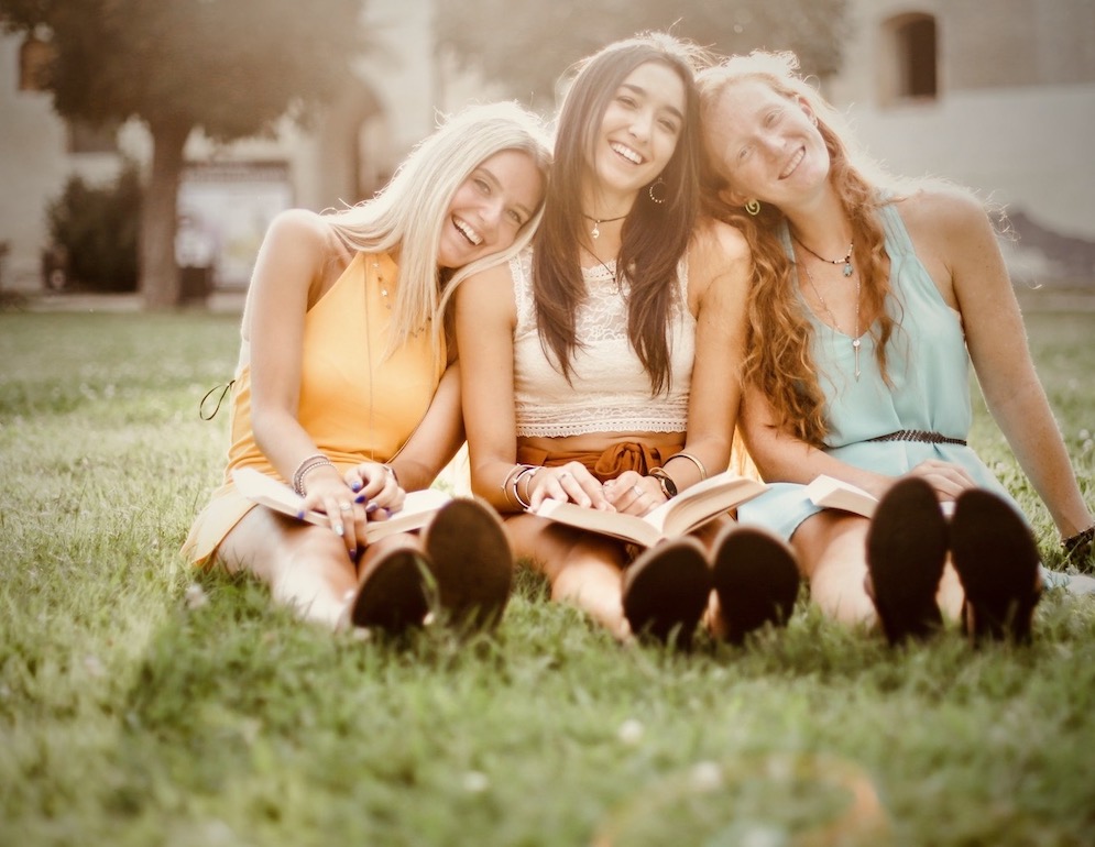 women on grass smiling in sunlight